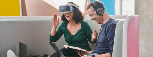 Femme avec casque VR et homme avec casque audio et ordinateur portable sur les genoux