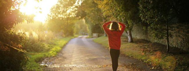 Personne en veste rouge se promenant dans la nature sous la lumière du soleil