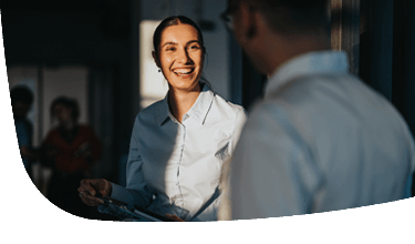 Vrouw met wit shirt die naar collega glimlacht
