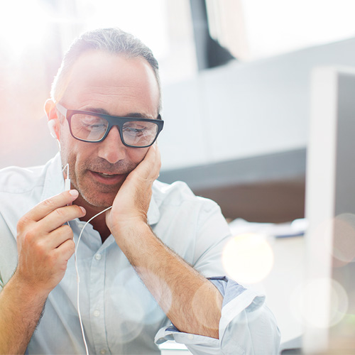 man with glasses talking in his earbuds