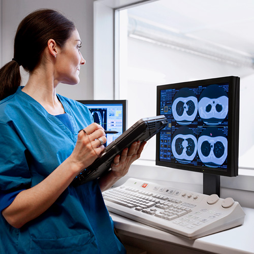 Doctor using a tablet and looking at a computer screen with medical images