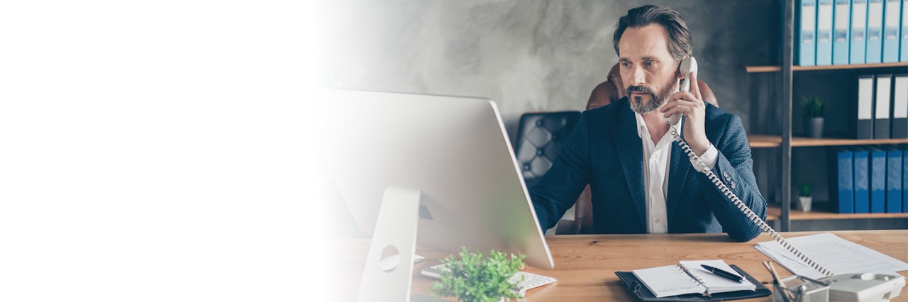 Man holding phone looking at desktop pc