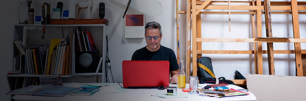 Man with glasses behind a red laptop in a studio