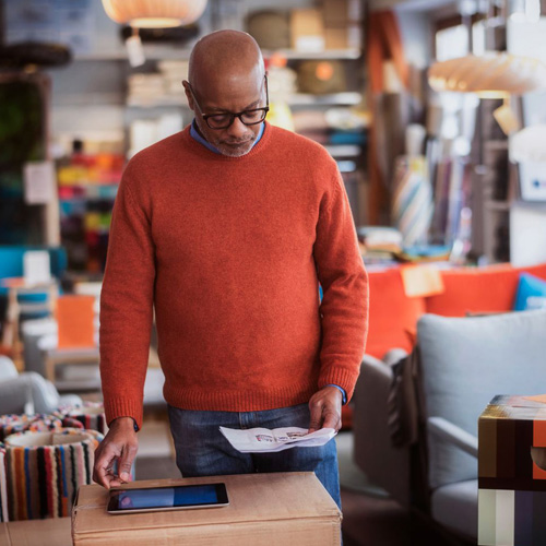 man in red sweater is reading the newspaper
