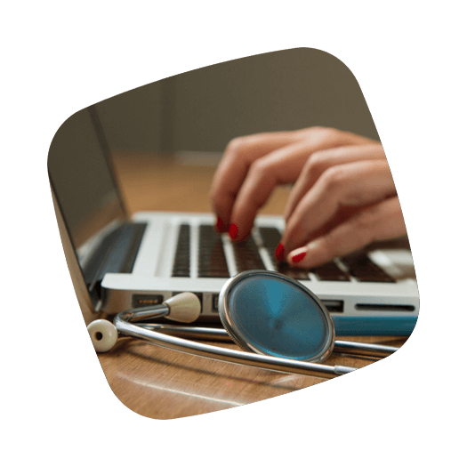 Close-up handen op laptop keyboard met sethoscoop in voorgrond