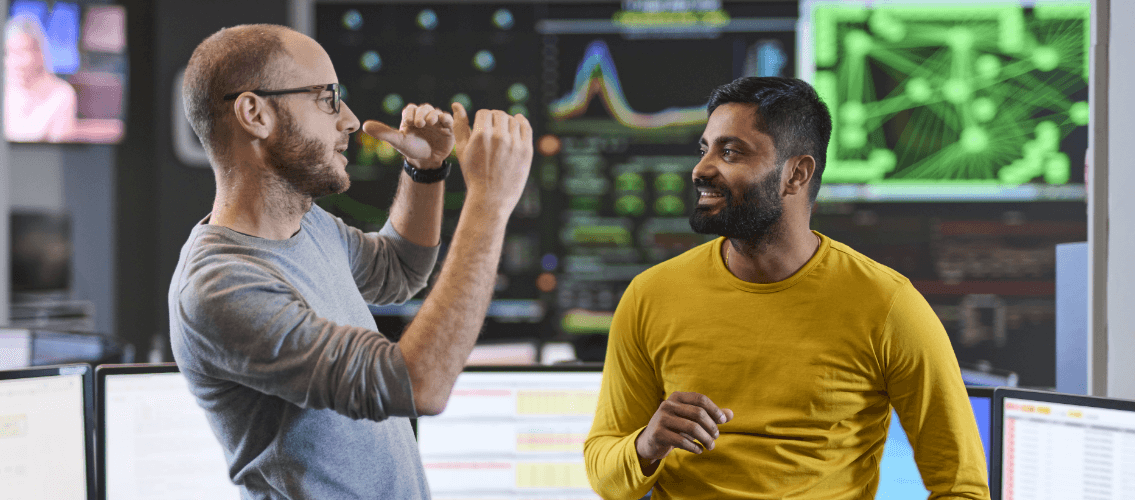 two male colleagues posing in front of computer screens