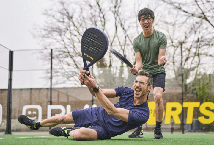two male coworkers playing padel outside