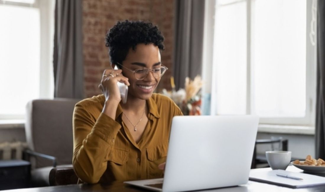 Woman in front of laptop with mobile phone